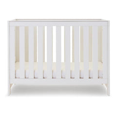 Obaby Nika MINI Cot Bed - White Wash side view, showing mattress base at lowest level